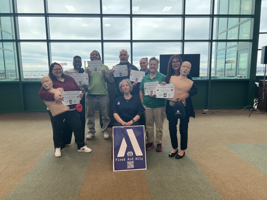 Christine is surrounded by a group of students holding their completion certificates of CPR,First Aid and AED Certification class.